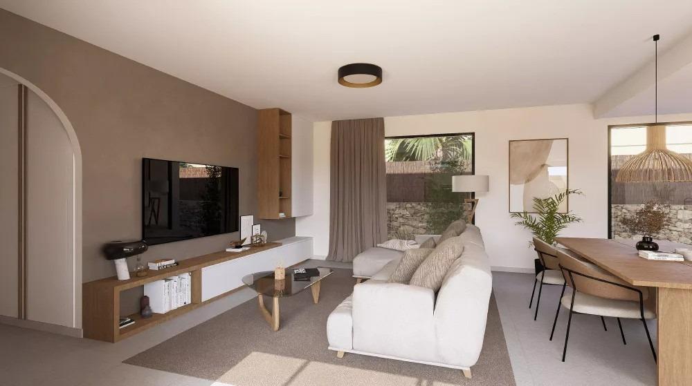 Modern living room with white sofa, glass coffee table, and wall-mounted TV unit in neutral tones; dining table to the right and large window letting in light.