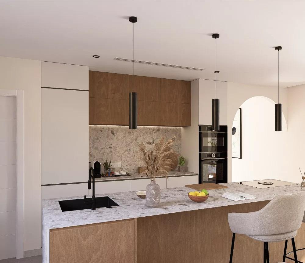 Modern kitchen with a marble island, black sink, and wooden cabinets; pendant lights above the island.