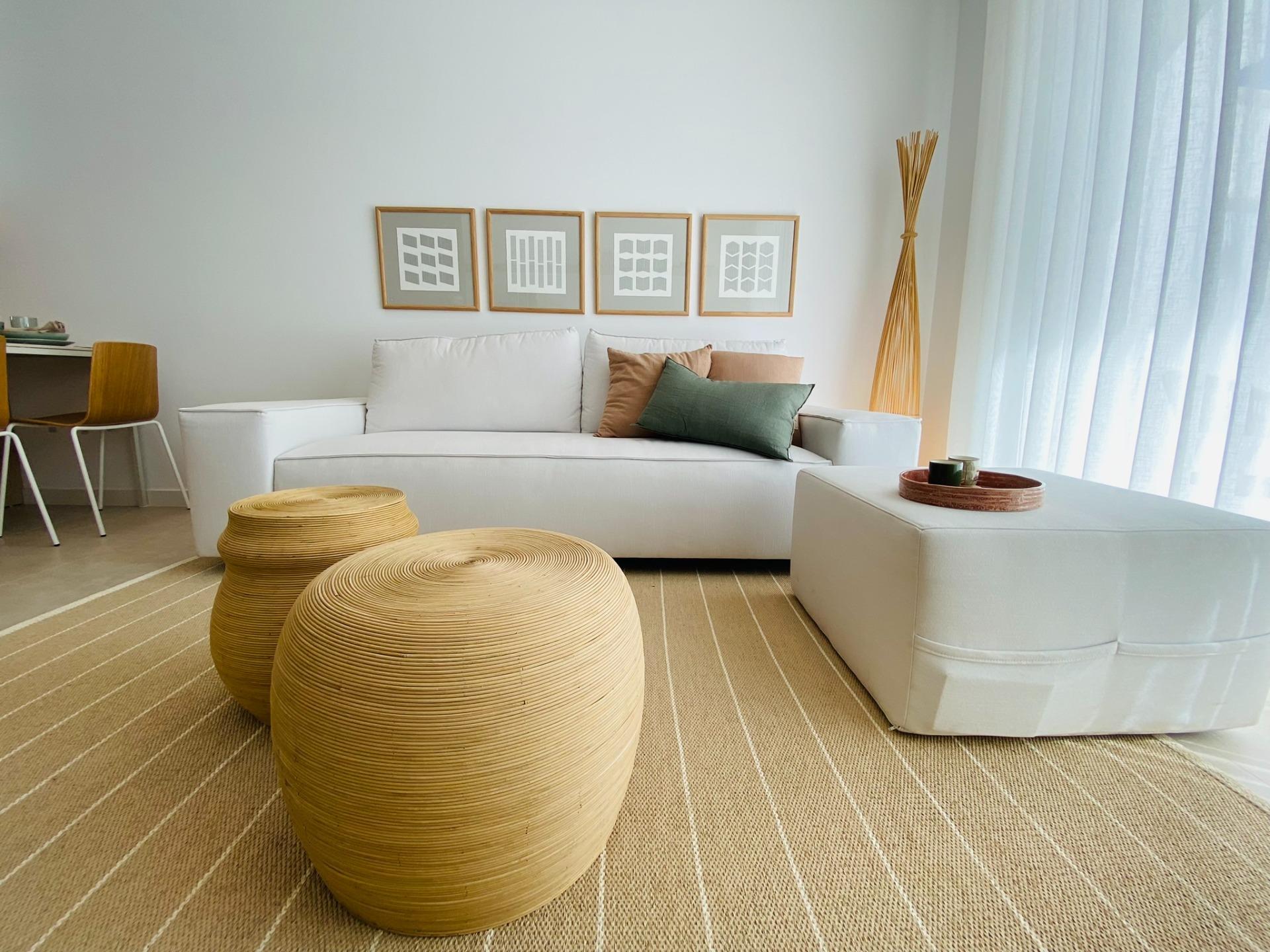 Bright living room with a white sofa, beige striped rug, and four framed geometric art pieces above the couch.