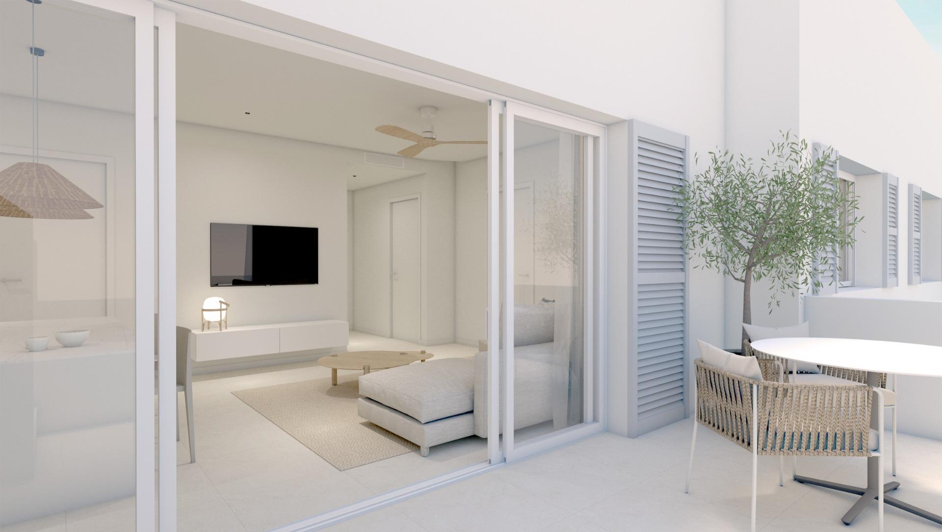 Bright, minimalist living room with a wall-mounted TV and white furniture, opening to a glass-walled patio.