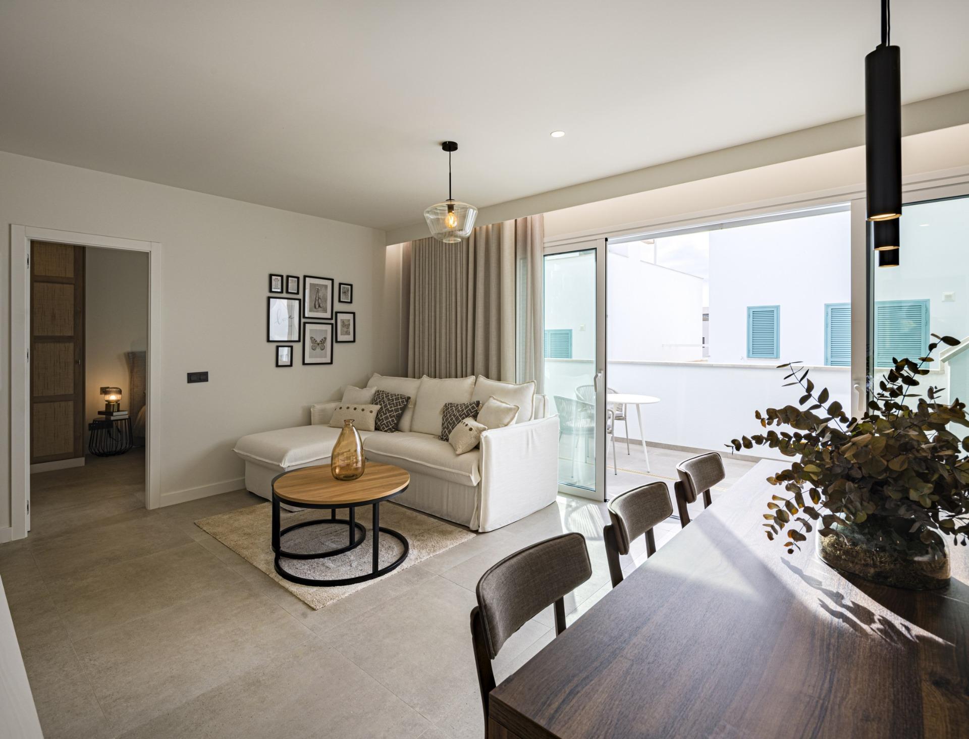 Open-plan living area with a beige sectional sofa, round coffee table, gallery wall, and sliding glass doors to a balcony.