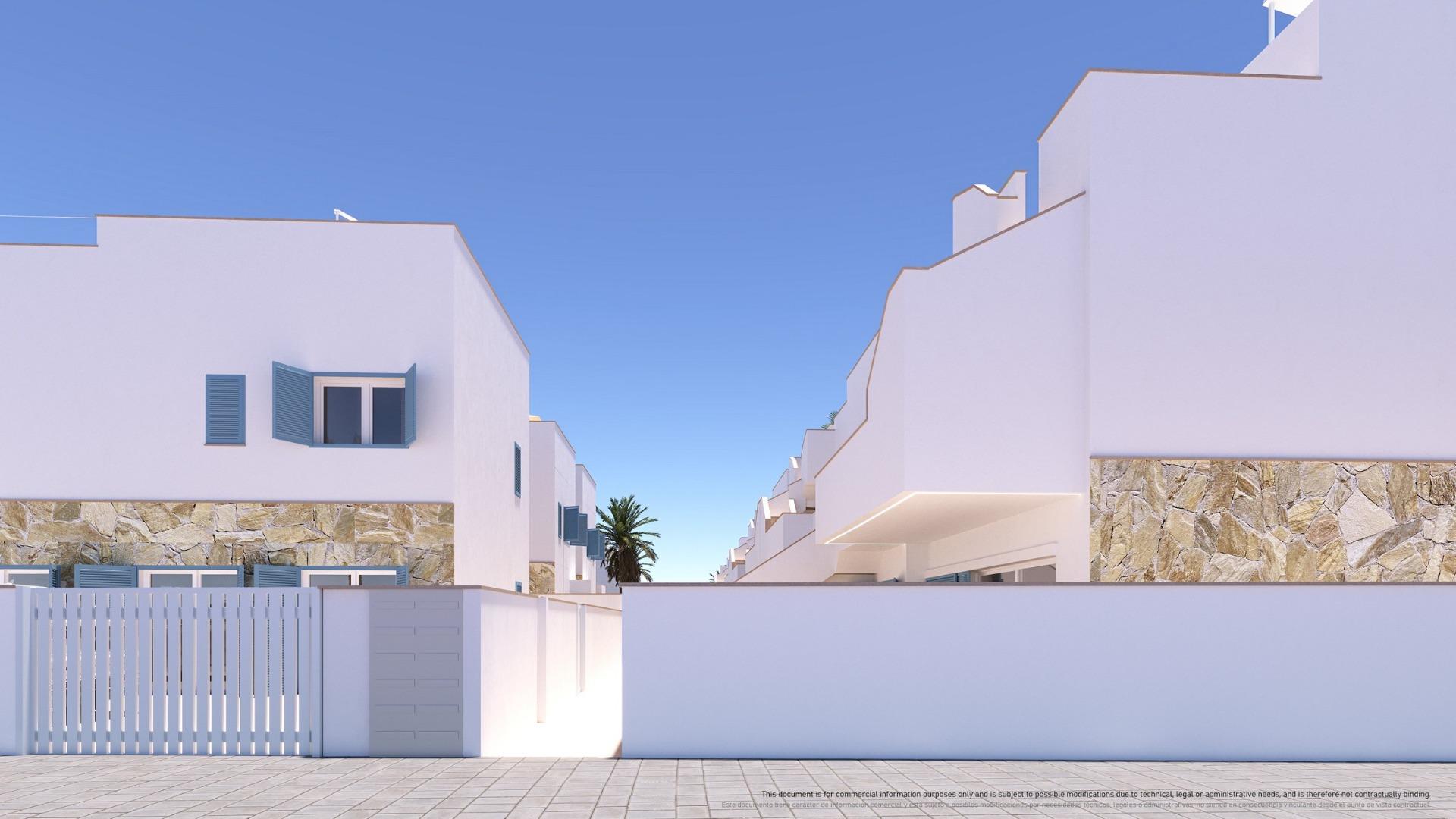 White Mediterranean-style buildings with stone bases and blue shutters along a sunny street; a palm tree in the distance under a clear blue sky.