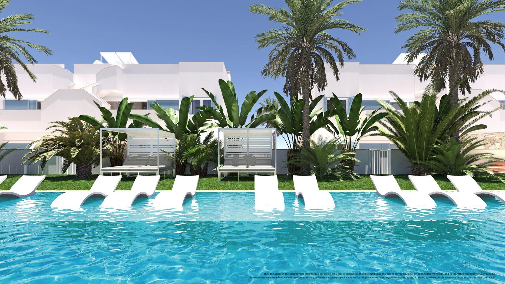 Poolside at a tropical resort: blue water, white lounge chairs, palm trees and white buildings in the background.
