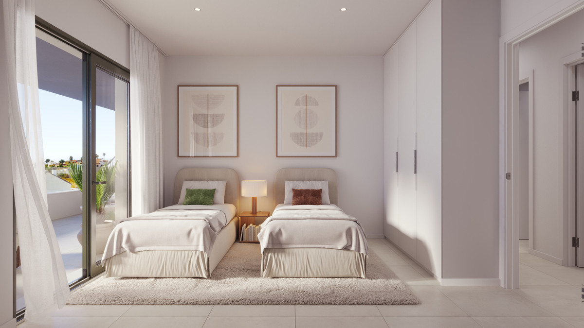 Twin bedroom with two beige upholstered beds, a shared nightstand with a lamp, white closets, and a balcony door.